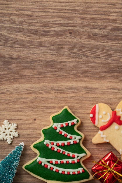 Top view of decorated Christmas gingerbread cookies with decorations on wooden table background with copy space, concept of holiday celebration.