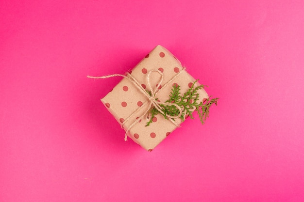 Photo top view of a decorated present with a bow on pink background