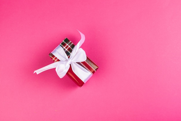 Top view of a decorated present with a bow on pink 