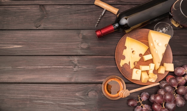 Vista dall'alto delizioso formaggio con bottiglia di vino e uva