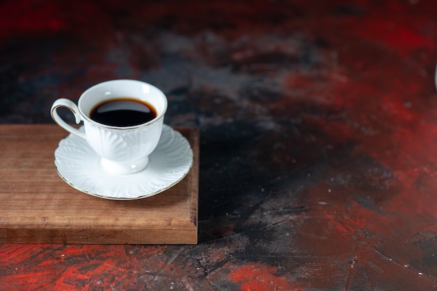 Top view of delicious coffee in a white cup on a brown wooden board on the right side on dark mix colors background with free space