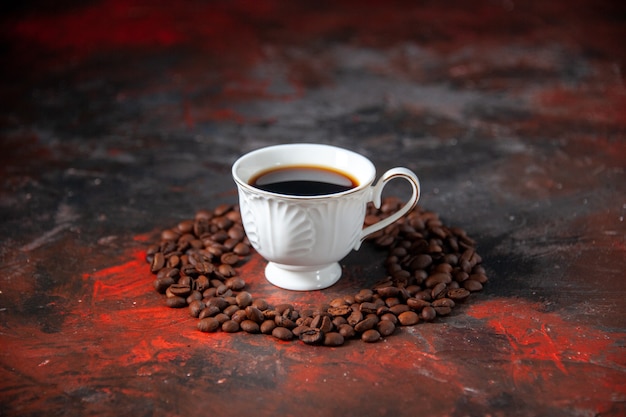 Top view of delicious coffee in a white cup and roasted beans around it on mix color background with free space