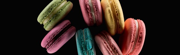 Top view of delicious fresh colorful French macaroons of different flavors isolated on black