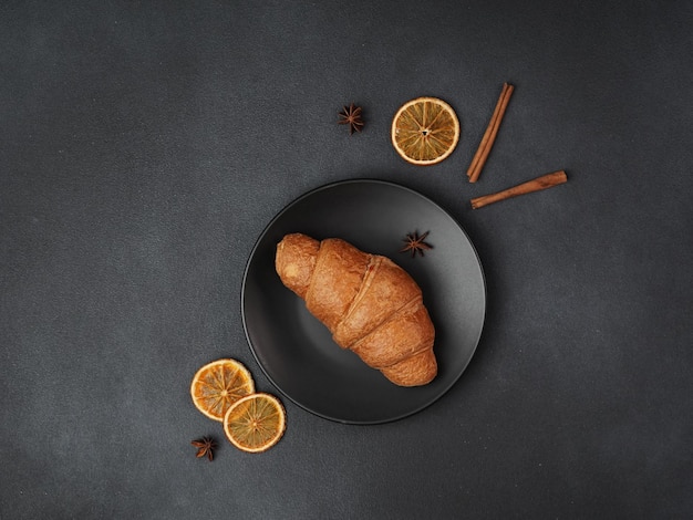 Top view of a delicious freshly baked Croissant Lying on a black Plate against a black background