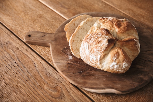 Top view delicious homemade bread or baked good lying on cutting board at wooden table