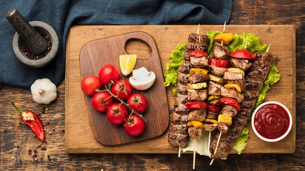 Вид сверху вкусного кебаба с мясом и овощами на разделочной доске