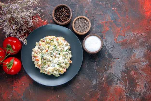 Vista dall'alto deliziosa insalata di cucina con condimenti di maionese e pomodori rossi su superficie scura