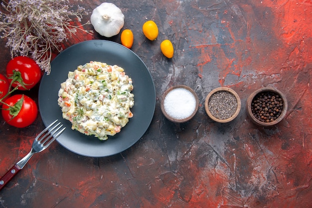 Vista dall'alto deliziosa insalata di cucina con condimenti di maionese e pomodori rossi su superficie scura