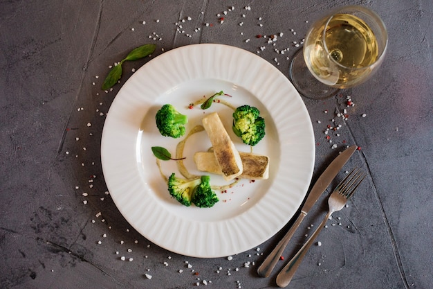 흰 생선과 브로콜리와 함께 맛있는 점심의 상위 뷰 접시에 와인 또는 주스 한 잔.