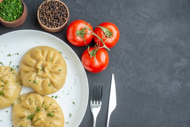 вид сверху вкусные пельмени с помидорами и приправами на темной поверхности