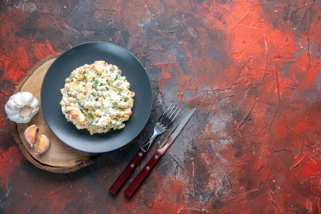 top view delicious russian salad with cutlery on dark surface