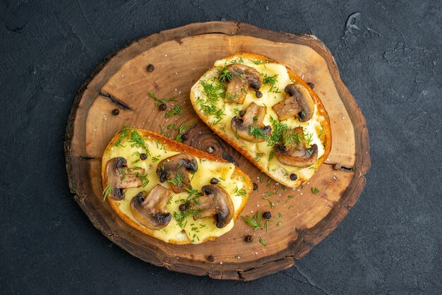 Top view of delicious snack with mushrooms on wooden board on black background with free space