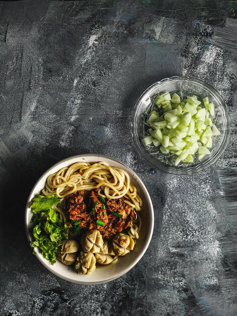 Foto vista dall'alto di deliziosi spaghetti con polpette e verdure serviti su un tavolo di pietra piatto