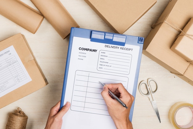 Top view of deliveryman making notes in delivery receipt at table