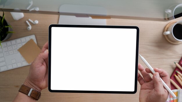 top view of designer using  tablet while working in modern rustic office room with computer and office supplies