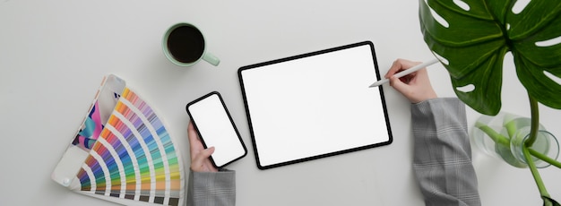 Top view of designer working on mock-up smartphone and tablet on marble table