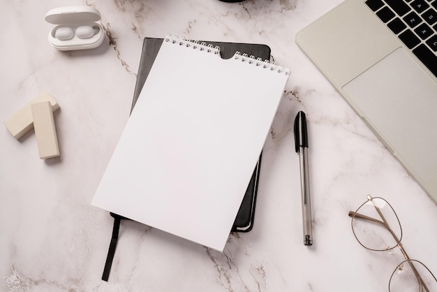 Top view desk arrangement. top view desktop blank calendar for\
mockup, notebook and laptop on light gray marble background, copy\
space for text