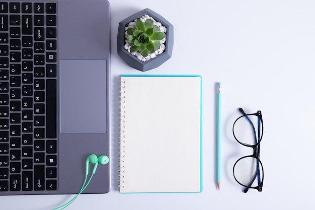 Vista dall'alto del desktop con laptop, penna e taccuino vuoto su sfondo bianco. concetto di obiettivi e piani aziendali