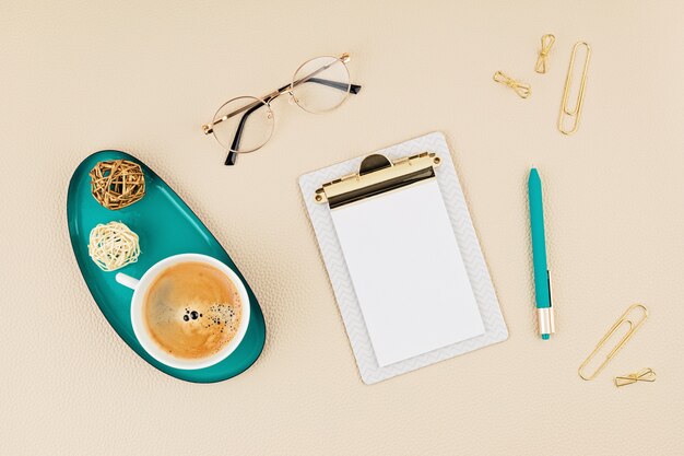 Top view over desktop with notepad, glasses and golden accessories. Home office, business woman, stylish workinf space concept. 