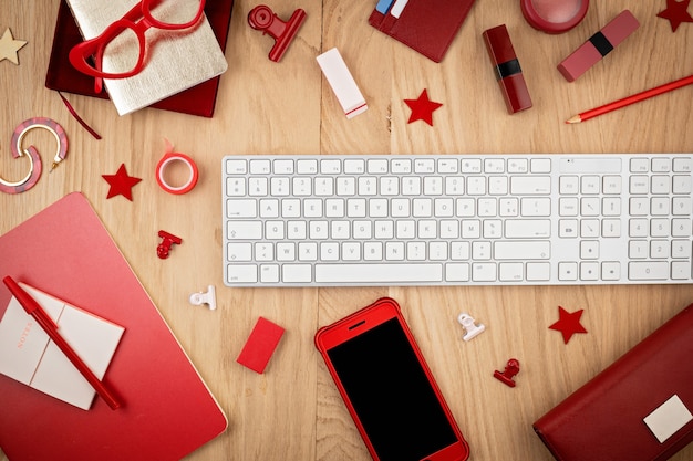 赤いオフィス文房具、スマートフォン、キーボードを備えたデスクトップの上面図。 latlay。オフィススペース、ホームオフィスのコンセプト