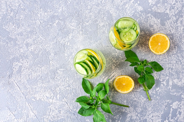Top view detox water drink with cucumber and lemon on light grey textured background