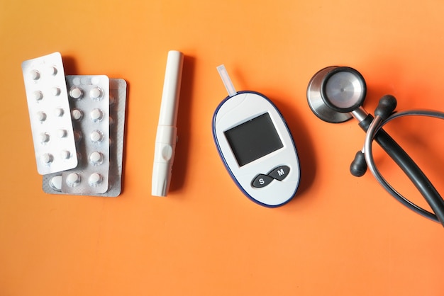 Top view of diabetic measurement tools and pills on orange