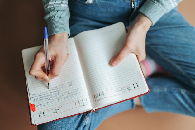 写真 認識できない大人のトップビュー日記手は、必要なものすべてをペンで紙に書き留めます