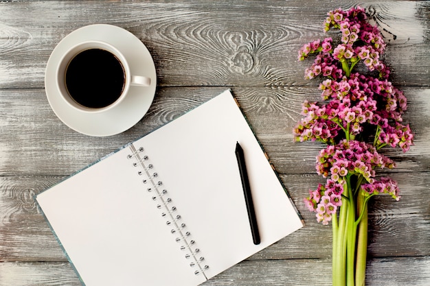 회색 나무 테이블에 일기 또는 노트북, 펜 및 커피와 보라색 꽃의 상위 뷰. 평면 디자인.