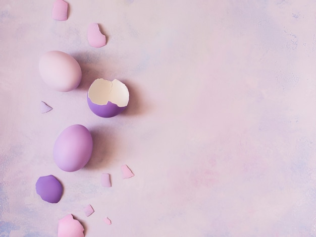 Top view of different colored eggs and scattered eggshell  on abstract background.