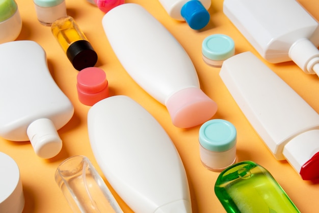 Top view of different cosmetic bottles and container for cosmetics on colored background. Flat lay composition with copy space.