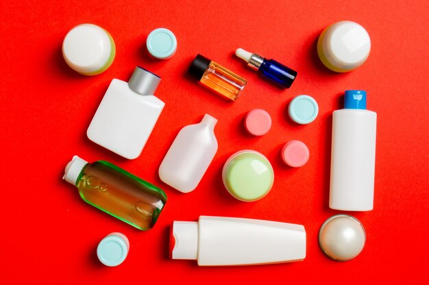 Top view of different cosmetic bottles and container for cosmetics on colored background flat lay