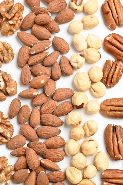 Top view of different delicious nuts on white background Space for text Nuts background Vertical photo