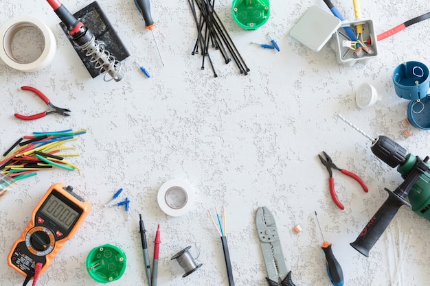 Top view of different electrical tools on white concrete\
background, flat lay. tools for an electrician, voltages and\
current measurements