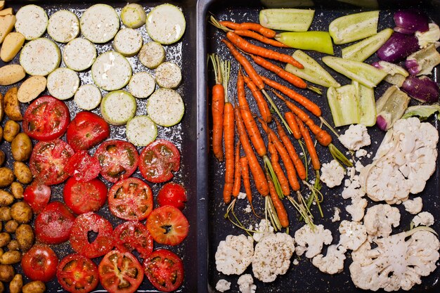 Photo top view of different raw vegetables for roasting on the baking tray. vegetarian menu concept