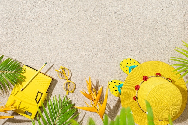 Top view of different summer objects on the sand with palm leaves background