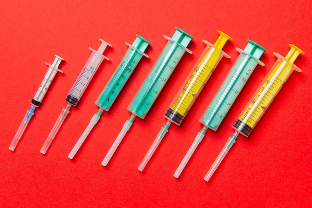 Photo top view of different syringes at red background medical injection concept with copy space