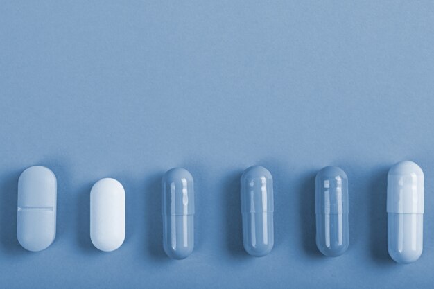Top view different tablets capsules on tinted background