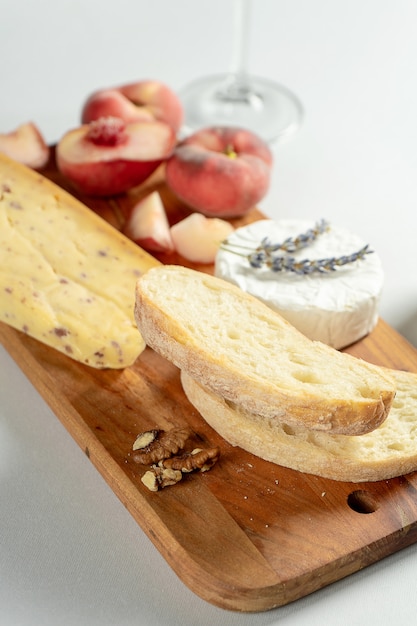 Top view different types of cheeses on wooden cutting board. Cheese with fig peach, honey, ciabatta and nuts, glass of red wine. Stylish food flat lay on grey background. Copy space. Soft focus