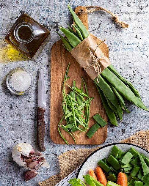 A top view of different vegetables green beans garlic and carrot on a kitchen table