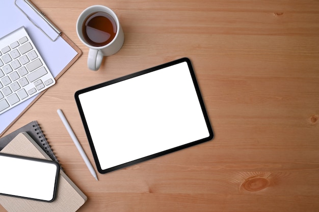 Top view digital tablet and mobile phone with white screen on wooden background.