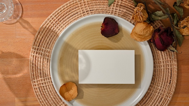 Top view of dining set with mock up name card on mock up ceramic plate and flower decorated on the table