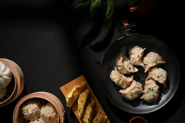 Vista dall'alto del tavolo da pranzo nel ristorante cinese con dimsum su piroscafo di bambù, gnocchi e focacce di maiale