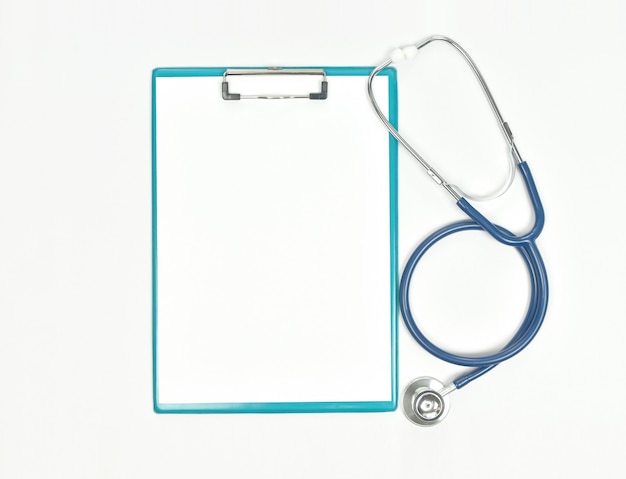 Top view of doctor desk table with stethoscope and blank paper on clipboard.