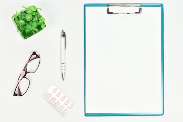 Top view of doctor desk with eyeglass, drug, pen and clipboard. copy space.