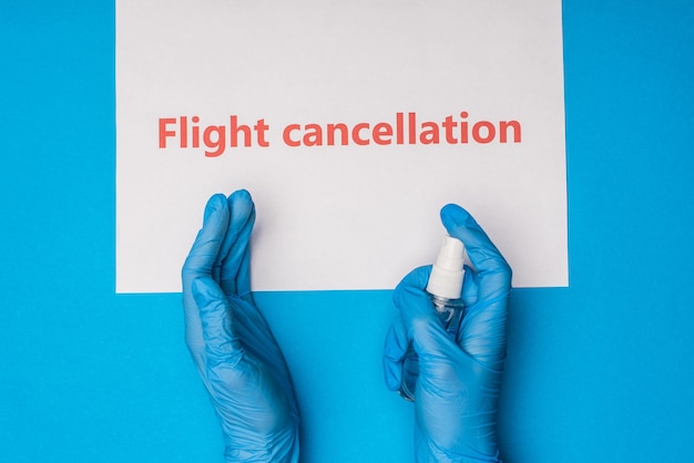 Top view of doctor holding bottle of hand sanitizer near card with flight cancellation lettering on