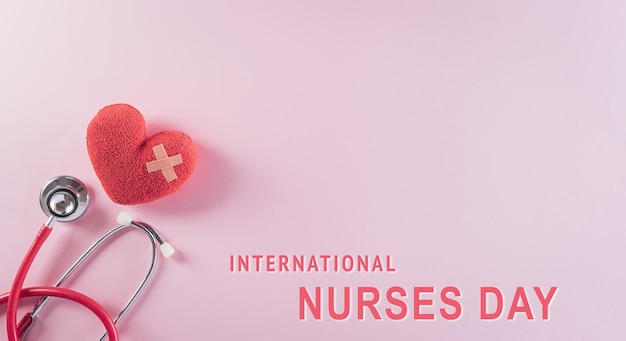 Top view of doctor stethoscope and red heart on pink background with international nurses day text