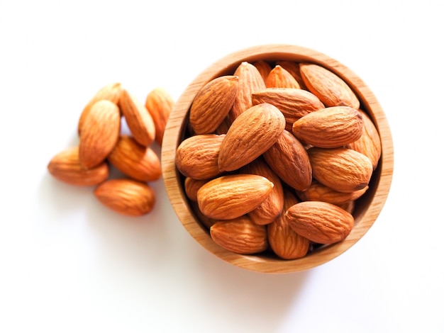 Top view of dried almonds in wooden bowl isolated