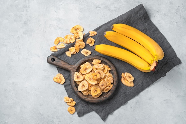 Top view of dried bananas on a grey kitchen cloth on white marble background