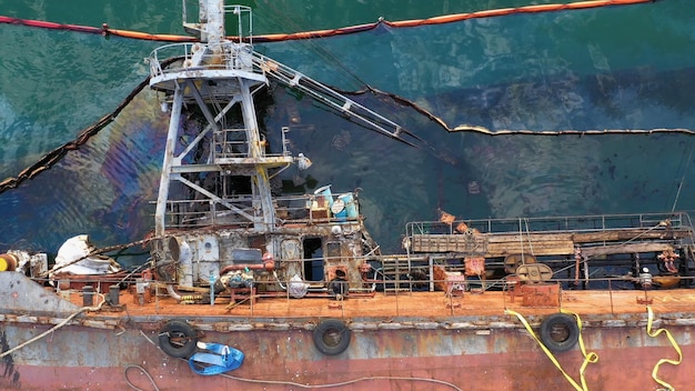 Top view drowned sunken overturned tanker ship on its edge in the shallow water