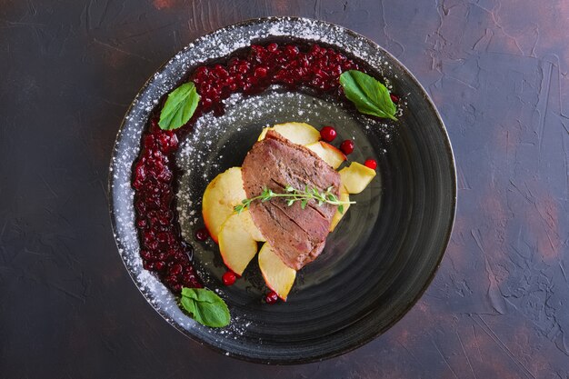 Top view of duck breast with apple and currant sauce